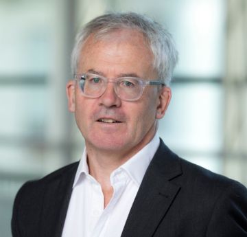 Dyn mewn crys yn gwenu i'r camera