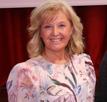 Menyw wedi gwisgo yn smart yn gwenu i'r camera