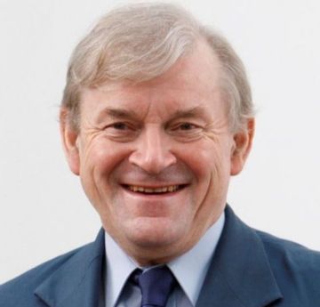 Dym mewn crys a tei yn gwenu i'r camera