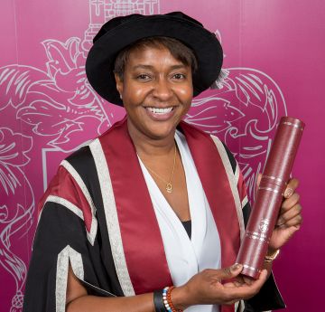 Manyw yn dal scrol yn gwenu wrth y camera