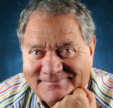 Dyn mewn crys streipiog gyda'i law ar ei en yn gwneu i'r camera