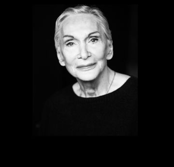 Menyw mewn gwisg du yn edrych ar y camera