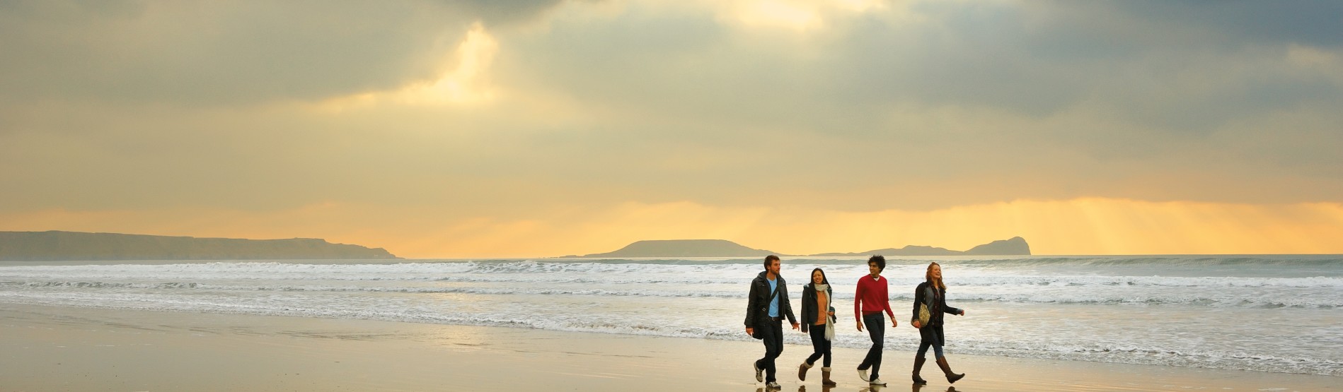 Myfyrwyr yn cerdded ar y traeth