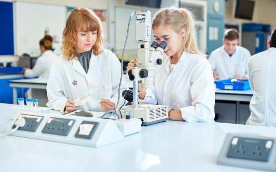 Female students looking into microscope