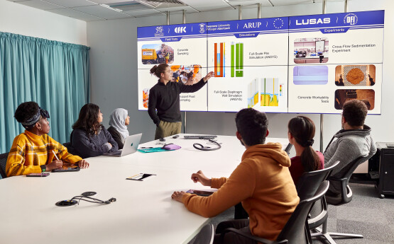Students in a science and engineering lecture, with lecturer presenting on a white board.
