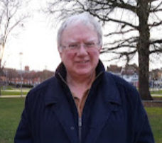 Delwedd o academydd, Athro Jonathan Bradbury y tu allan yn sefyll o flaen coeden.