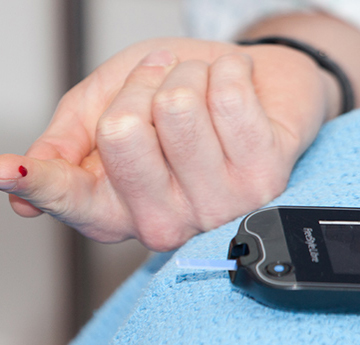 Blood Glucose Monitor and droplet of blood on finger