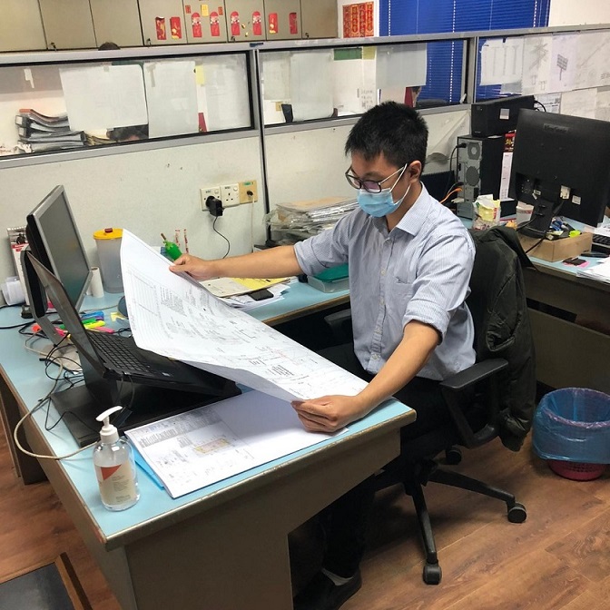 Man sat at a desk with a large sheet in his hands