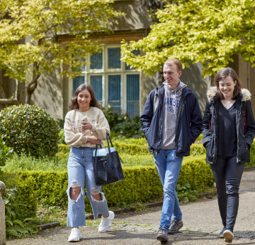 three students walking by the abbey building, singleton campus