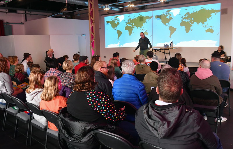 Siaradwr ar lwyfan a thorf o bobl