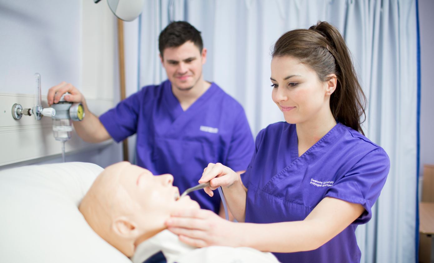 Two students in scrubs working on a patient model