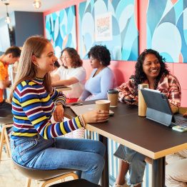 Delwedd o fyfyrwyr yn astudio ac yn sgwrsio mewn caffi ar Gampws Singleton.
