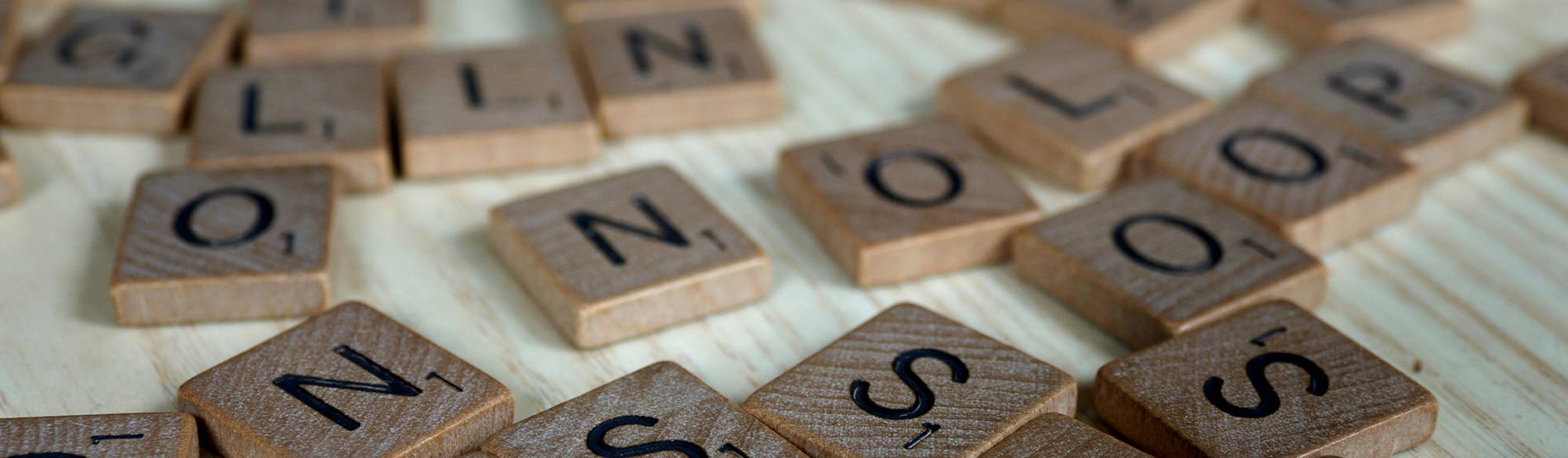Tyleau Scrabble wedi eu gwasgaru ar draws bwrdd.