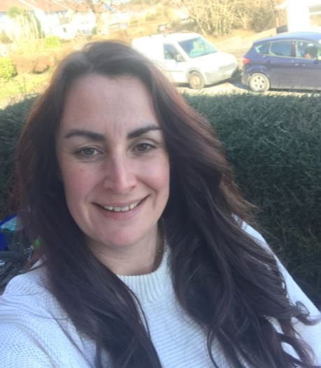 Woman with long brown hair takes selfie in garden
