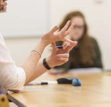Students in meeting image focused on hands