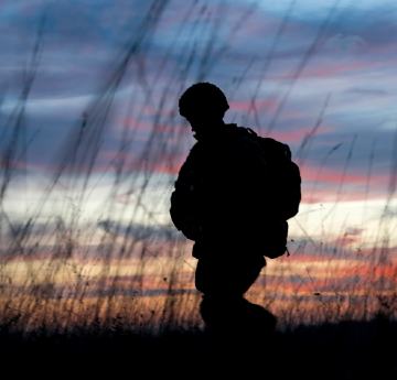 Silhouette of soldier walking cross-country