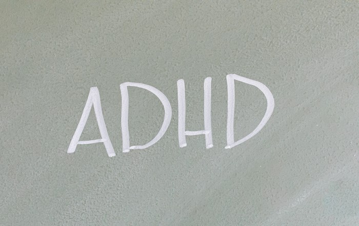 Bwrdd du â'r acronym ADHD wedi'i ysgrifennu arno mewn sialc.