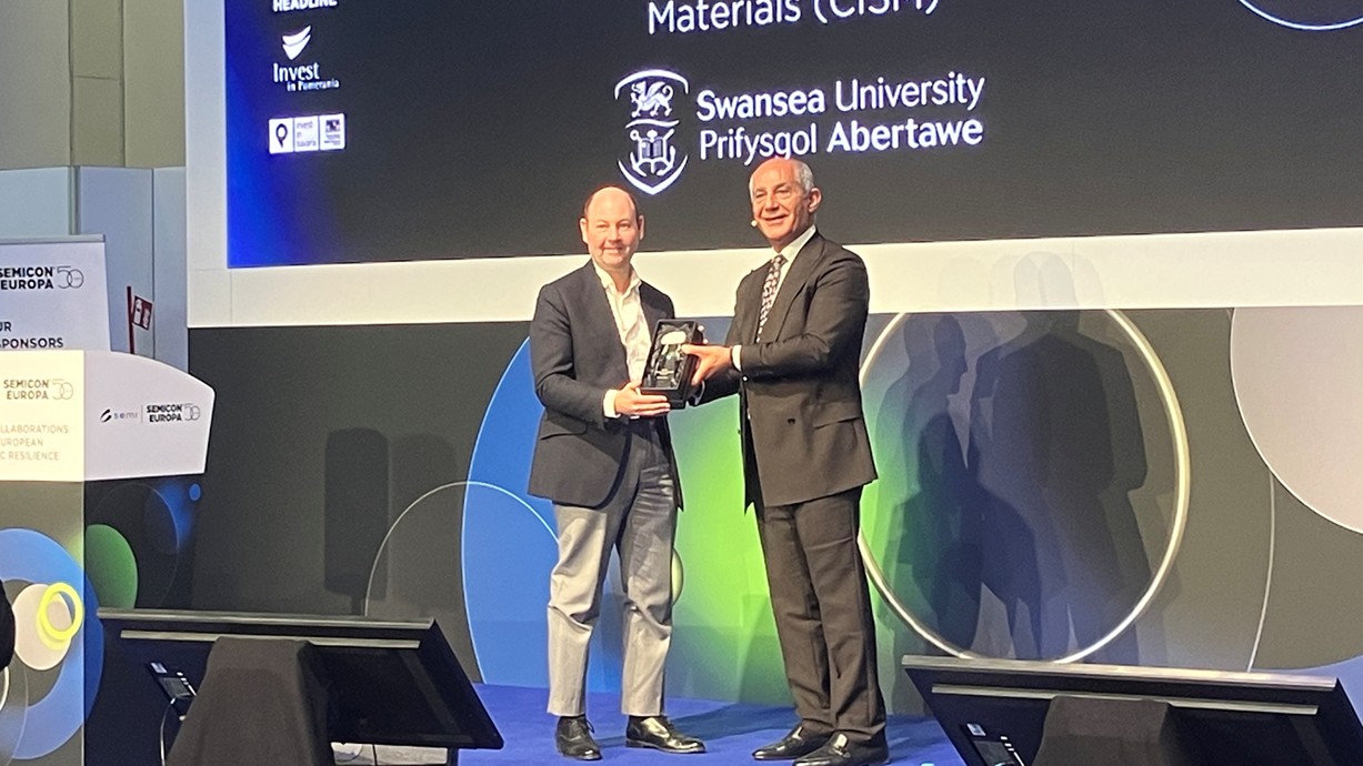 Llun o'r Athro Guy ar y llwyfan yn y CxO Executive Summit i dderbyn gwobr SEMI Academia Impact.