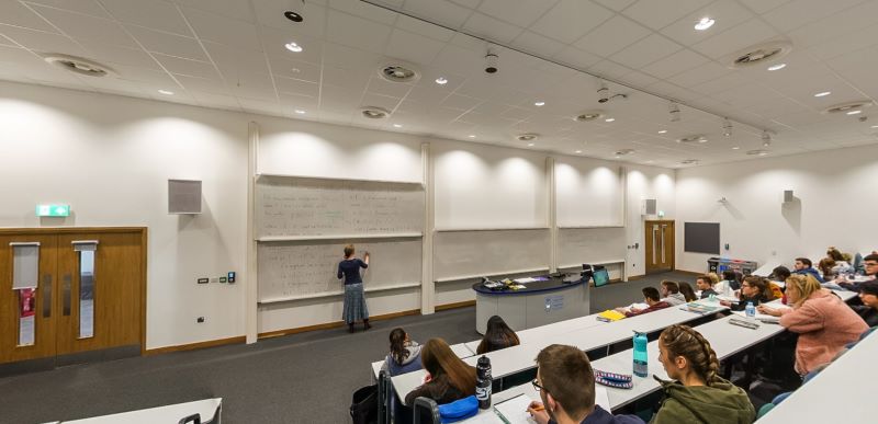 Theatr ddarlithio gyda seddi, darlithwyr yn ysgrifennu ar fyrddau