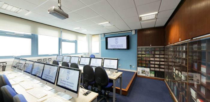 Labordy cyfrifiaduron Mac gyda sgrin gyflwyno a llyfrgell gyfeirio