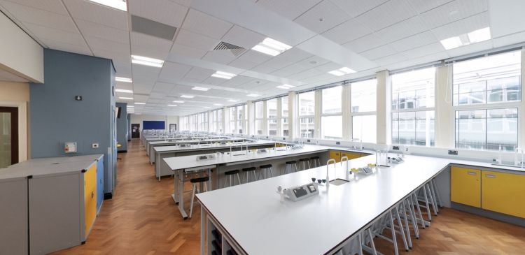 Lab addysgu gwyddoniaeth gyda meinciau gwaith, stolion, sinc a ffenestri mawr