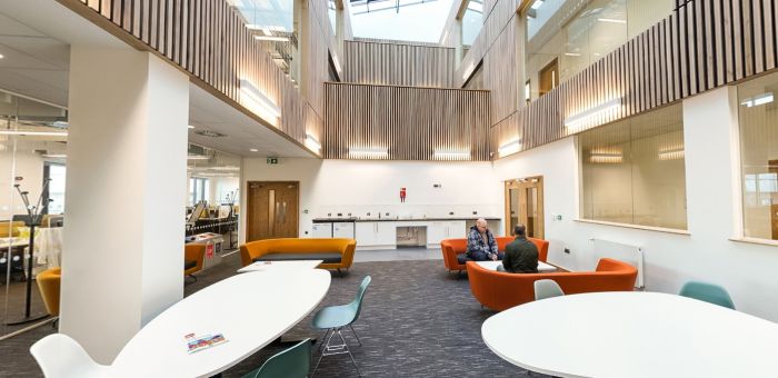 Man astudio cydweithredol gyda byrddau, seddi hamddenol a llawr canolradd agored
