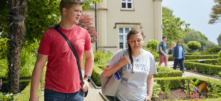 A young man in a red shirt and a female in a white t-shirt walking through the Singleton Abbey grounds