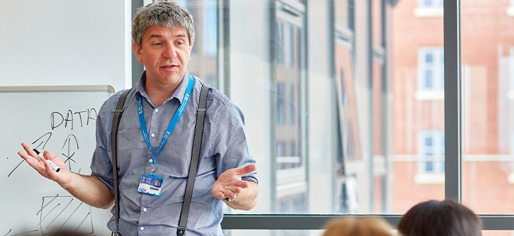 Darlithwr yn siarad i grwp o fyfyrwyr