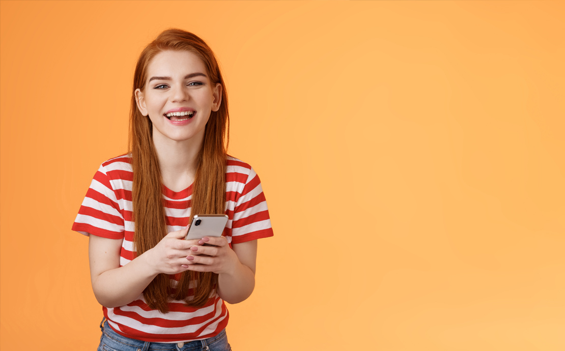 A smiling girl using a mobile phone