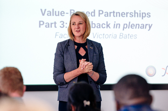 Menyw yn cyflwyno o flaen ystafell o bobl