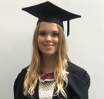 female smiling in graduation cap and gown