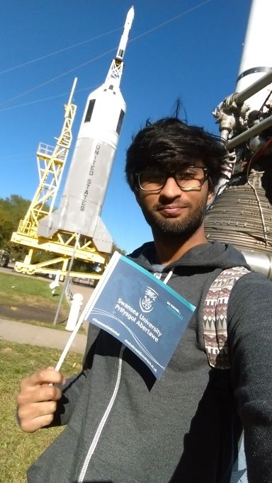 Student holding a Swansea University flag with NASA shuttle in background