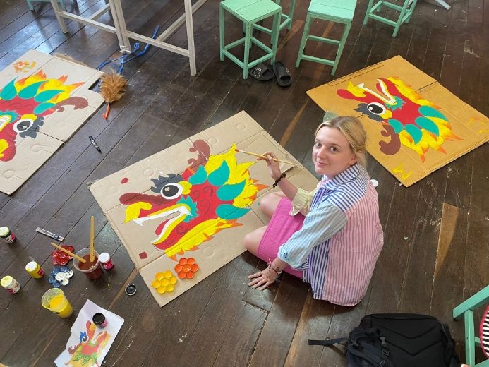 student painting on cardboard on the floor