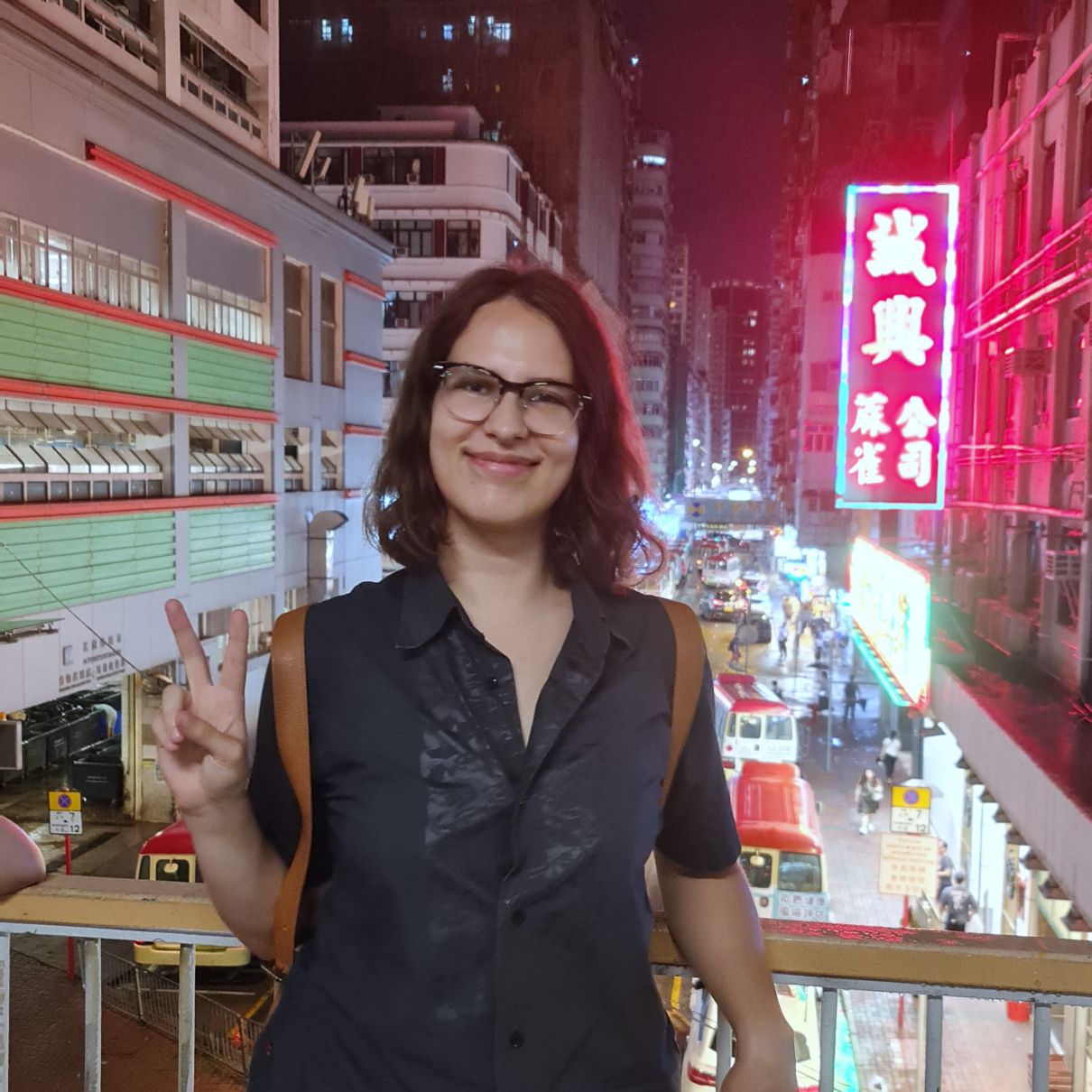 Student standing in front of Hong Kong landscape.
