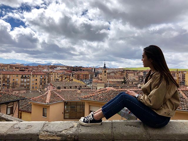 Girl sitting on wall with Spain in the background