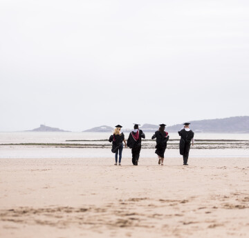 Graduates walking away on the beach