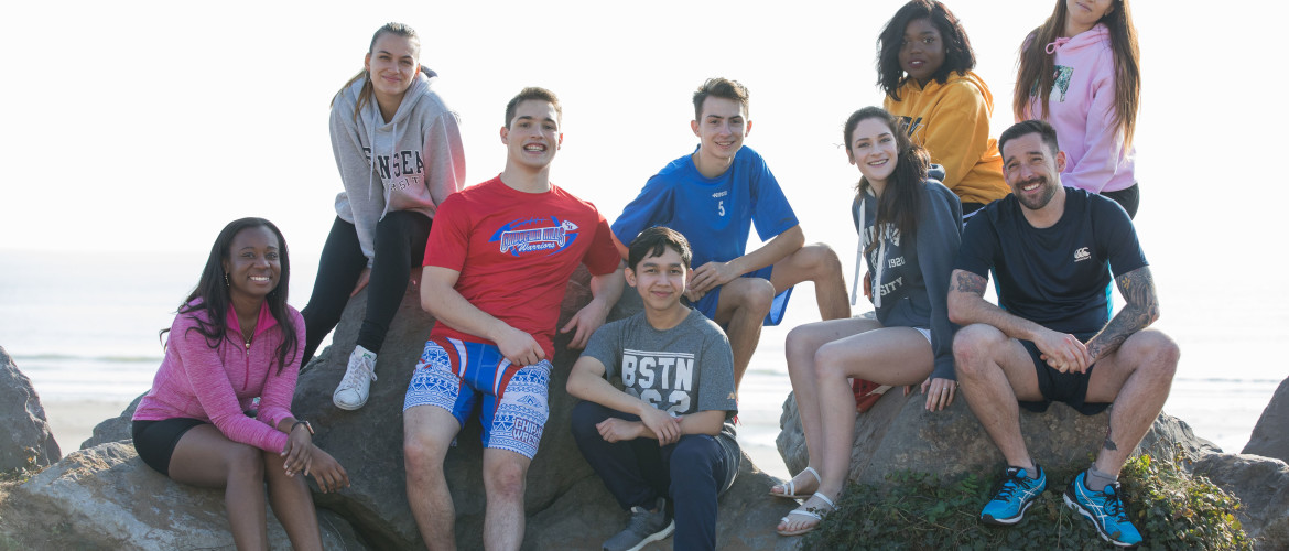 Group of smiling students sitting on sand dunes
