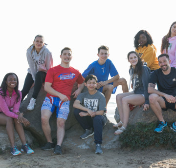Group of students on beach smiling at the camera.