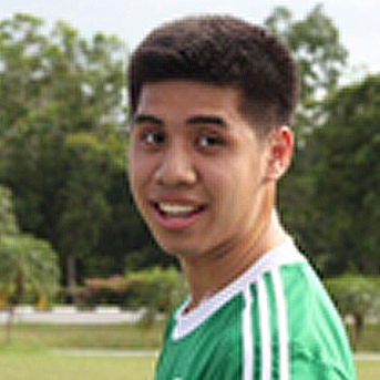 Smiling male Bruneian student looking sideways at camera wearing a green football shirt