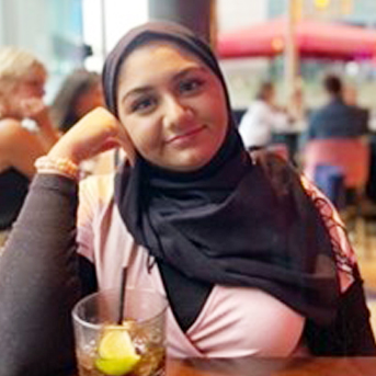 Female student from Egypt smiling at the camera at a table in a restaurant. 
