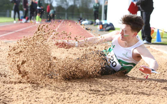 Man jumping in sand pit.