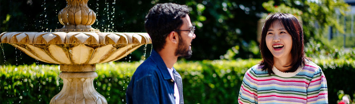 Two students sitting in front of a fountain