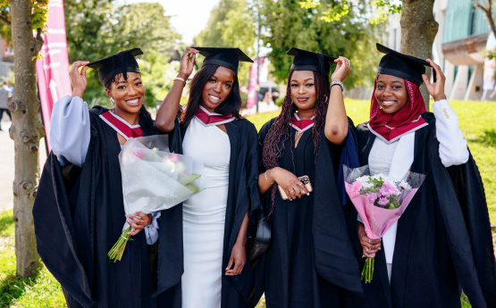 .Four recent graduates in their graduation gowns