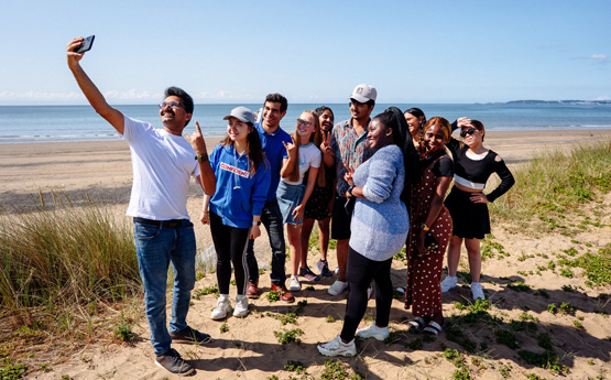 A group of students from all over the world taking a selfie on Swansea Bay