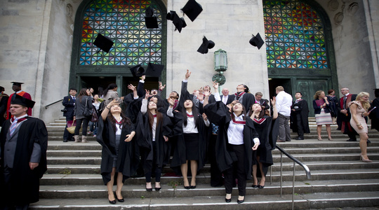 Group of recent graduates throwing graduation caps into the air.