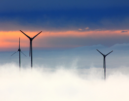 Three wind turbines above clouds