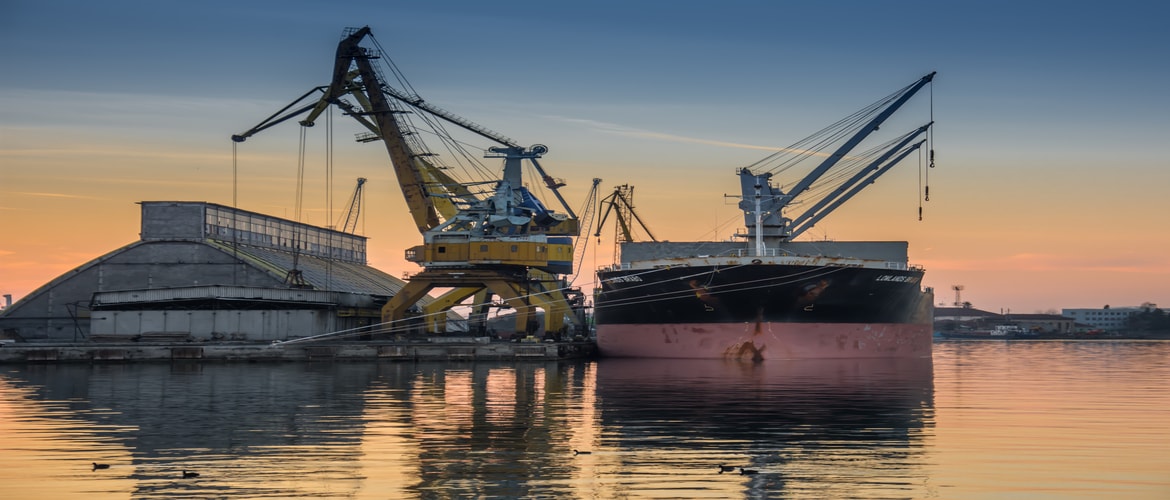 Image of shipping transport vessels by a sunset sky.