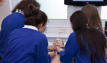 Some school children investigating a resuscitation doll