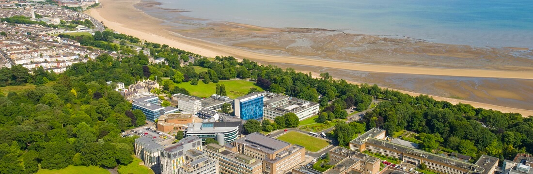 Aerial shot of the Singleton Campus surrounded by trees and parks and with the beach and Swansea Bay close by