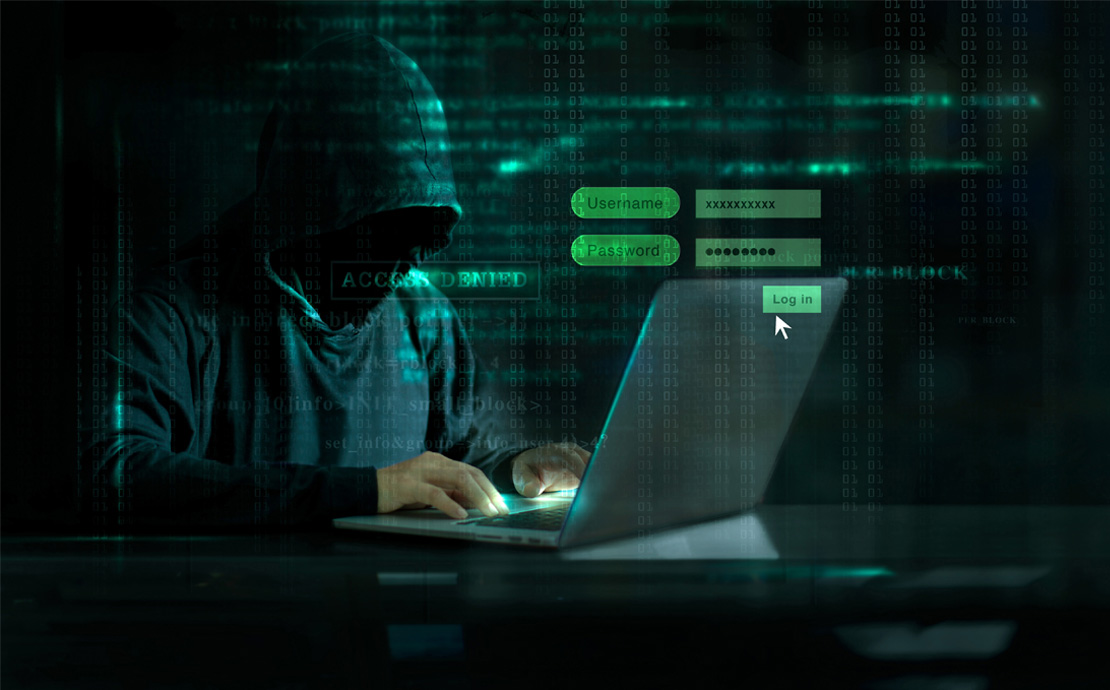 A hooded person on a laptop